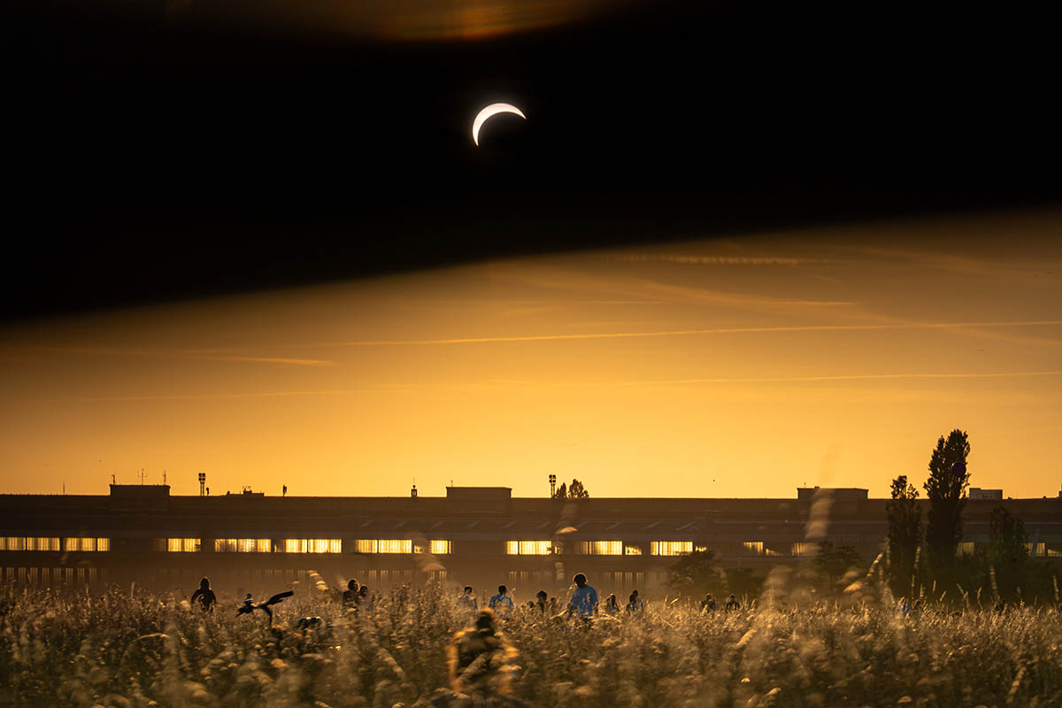 Das Foto von © Björn Obmann zeigt die vom Mond teilweise verdeckte Sonne in Richtung der Flughafengebäude gesehen